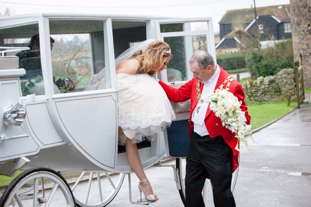 Toastmaster helping Bride down from carriage